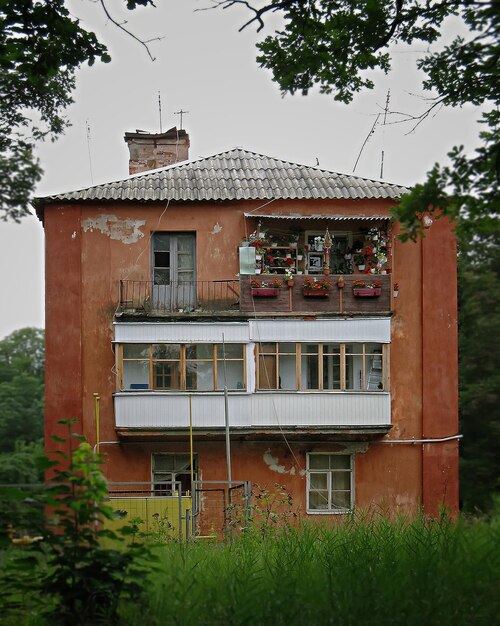 old small red house with balconies flowers background green trees grass 651117 96